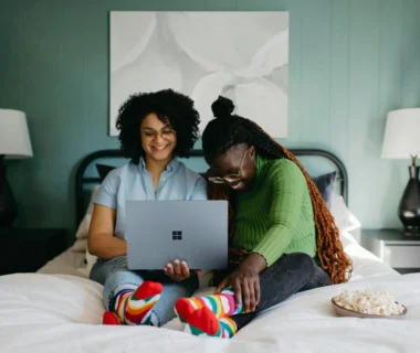 a woman sitting on a bed using a laptop