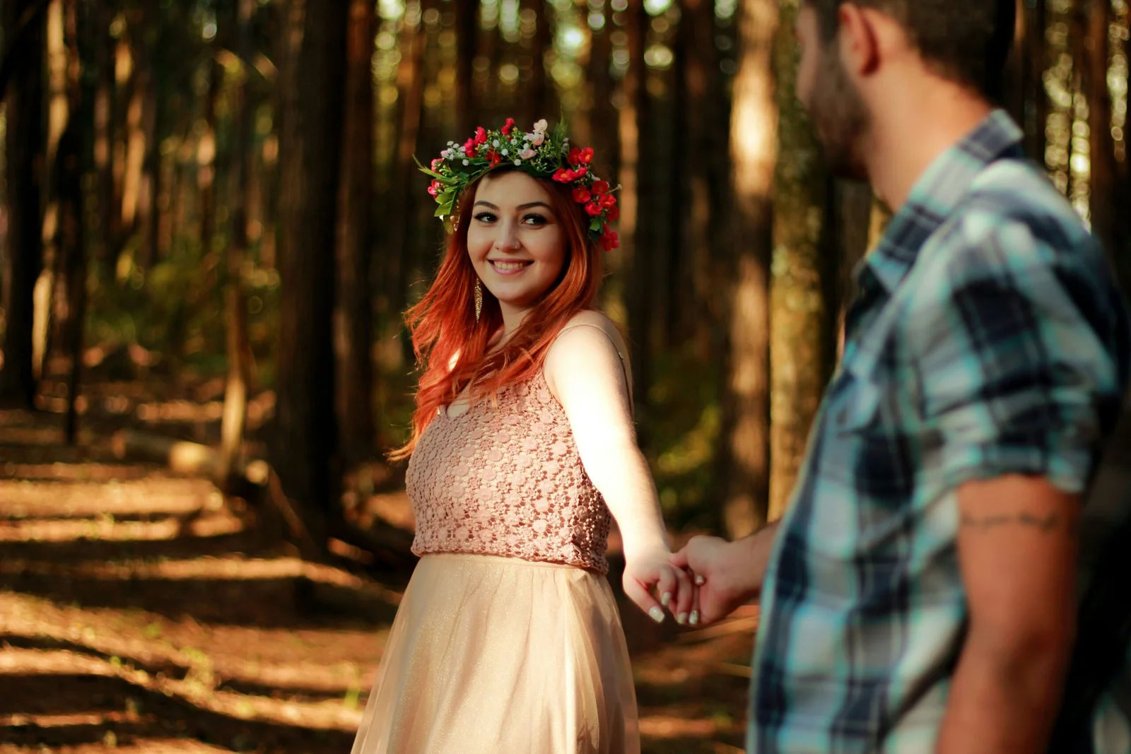 couple holding hands while standing near tree barks